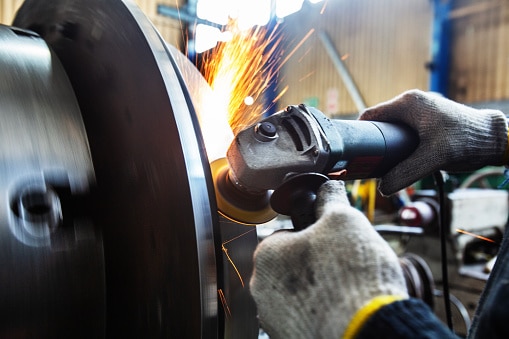 Close-up of hands using and angel grinder in a factory